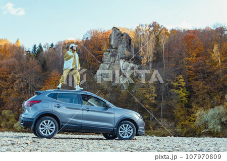 happy woman at car roof enjoying the view of autumn river in carpathian mountains happy woman at car roof enjoying the view of autumn river in carpathian mountains 107970809