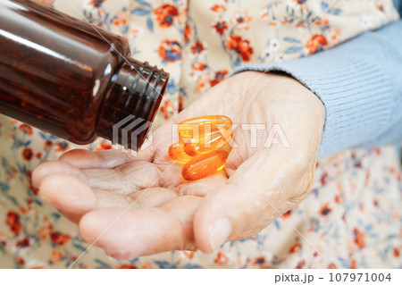 Asian elderly woman holding pill drug in hand, strong healthy medical concept. Asian elderly woman holding pill drug in hand, strong healthy medical concept. 107971004