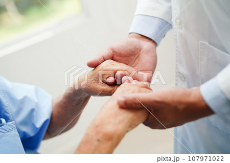Doctor holding hands Asian elderly woman patient, help and care in hospital. 107971022