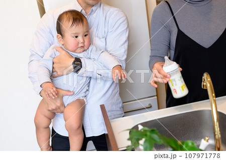 父親に抱っこしてもらい赤ちゃんに冷やしたミルクを飲ませる母親 あやす 乳幼児 イクメン 0歳乳幼児 父親に抱っこしてもらい赤ちゃんに冷やしたミルクを飲ませる母親 あやす 乳幼児 イクメン 0歳乳幼児 107971778