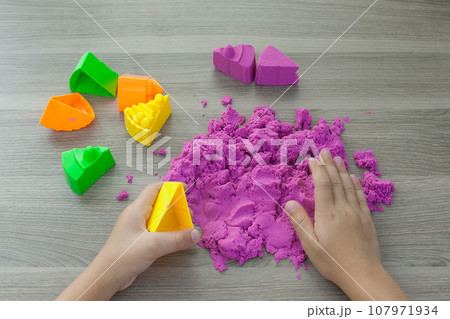 Little girl playing with bright kinetic sand at table indoors, closeup 107971934