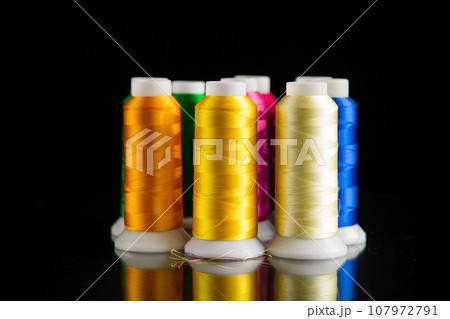 set of different color sewing threads,on black background. 107972791