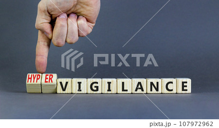 Vigilance or hypervigilance symbol. Concept words Vigilance Hypervigilance on wooden blocks. Beautiful grey background. Psychologist hand. Psychology vigilance hypervigilance concept. Copy space. 107972962