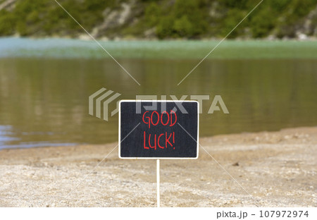 Good luck symbol. Concept words Good luck on beautiful black chalk blackboard. Beautiful mountain lake background. Business, motivational good luck concept. Copy space. 107972974