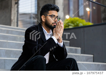 Indian businessman freelancer wishing luck praying asking blessing help forgiveness in downtown city Indian businessman freelancer wishing luck praying asking blessing help forgiveness in downtown city 107975437