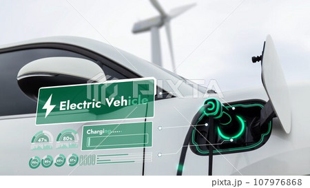 Electric car recharging energy from charging station in wind turbine farm.Peruse Electric car recharging energy from charging station in wind turbine farm.Peruse 107976868