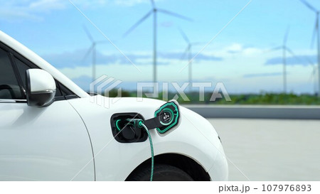 Electric car recharging energy from charging station in wind turbine farm.Peruse 107976893