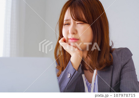 職場のデスクで辛そうな表情をしている女性 107978715