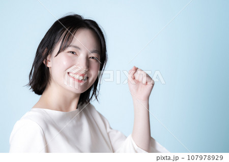 背景が爽やかなブルーグリーンの女性のイメージ　ガッツポーズ 107978929