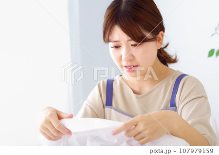 汚れたワイシャツを見つめる若い女性 107979159