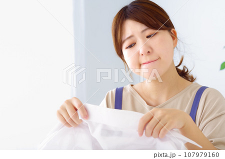 汚れたワイシャツを見つめる若い女性 107979160