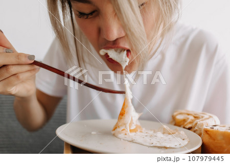Funny face of woman putting breakfast into her mouth. Concept of dietary. Funny face of woman putting breakfast into her mouth. Concept of dietary. 107979445