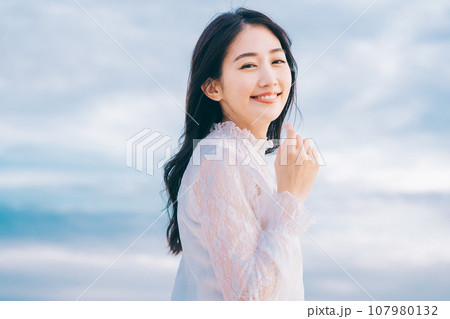 青空背景の若い女性のビューティーイメージ 107980132