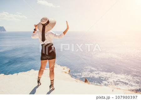 Woman sea hat. Business woman in yellow hat freelancer working over blue sea beach. Girl relieves stress from work. Freelance, digital nomad, travel and holidays concept 107980397