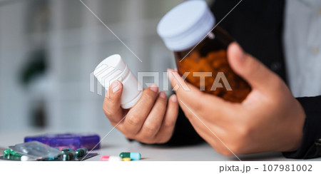 Woman hold bottle of drug tablet painkiller or vitamin supplement reading label ready to organizing medicine at home. medication healthcare concept 107981002