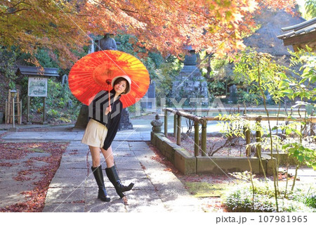 秋の神社の境内でポーズをとる若い女性 秋の神社の境内でポーズをとる若い女性 107981965