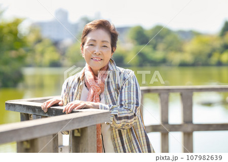 池のほとりを歩くシニア女性の写真素材 [107982639] - PIXTA
