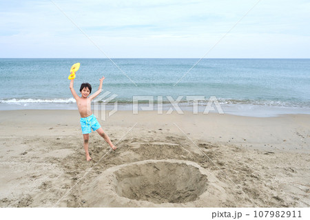 Children dig a hole in the sand on the seashore. 107982911