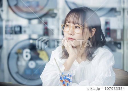 コインランドリーでお茶をする若い女性 107983524