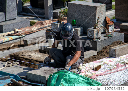 霊園内でお墓の墓所内整備工事を行う職人 107984532