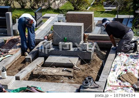 霊園内でお墓の墓所内整備工事を行う職人 107984534