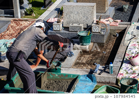 霊園内でお墓の墓所内整備工事を行う職人 107984545