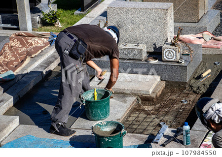 霊園内でお墓の墓所内整備工事を行う職人 107984550