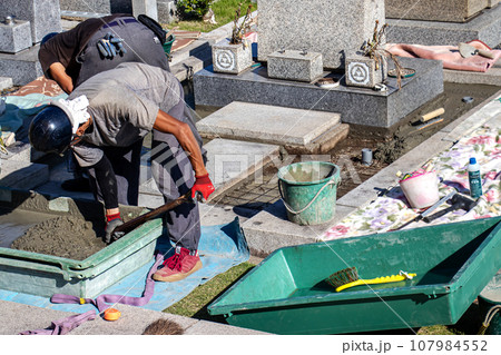 霊園内でお墓の墓所内整備工事を行う職人 107984552