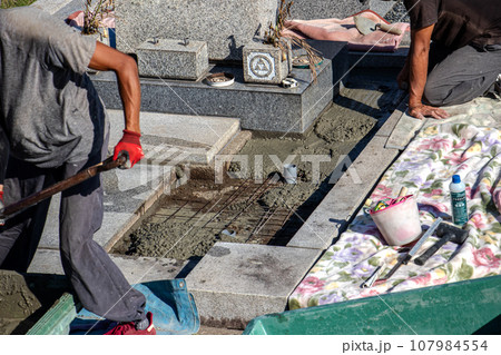 霊園内でお墓の墓所内整備工事を行う職人 107984554