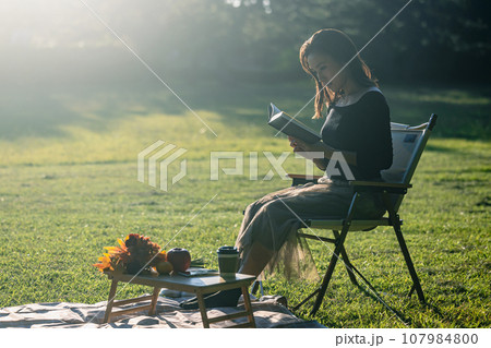 晴れた日の夕方、逆光のなか読書を楽しむ若い女性 晴れた日の夕方、逆光のなか読書を楽しむ若い女性 107984800