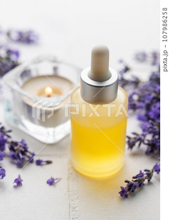 Lavender natural essential oil and fresh lavender on a white tile background. Lavender natural essential oil and fresh lavender on a white tile background. 107986258