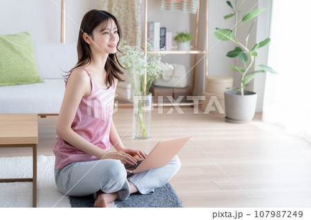 リビングでパソコンを見る若い女性 リビングでパソコンを見る若い女性 107987249