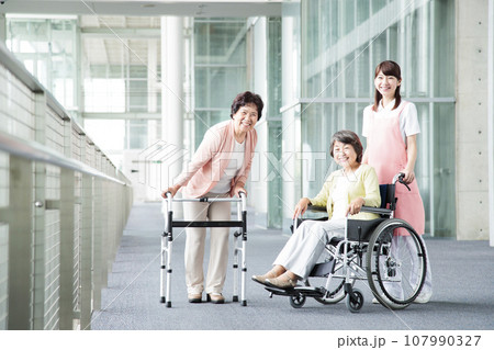 介護施設で高齢者を介護する若い介護士 介護施設で高齢者を介護する若い介護士 107990327