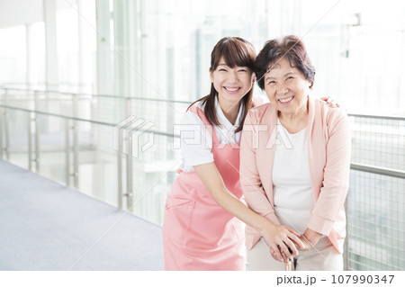 介護施設で高齢者を介護する若い介護士 107990347