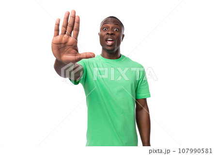 american surprised brunette man with short haircut dressed in light green t-shirt says stop american surprised brunette man with short haircut dressed in light green t-shirt says stop 107990581