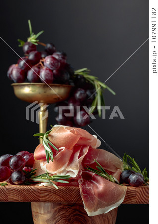 Prosciutto with grapes and rosemary. Prosciutto with grapes and rosemary. 107991182