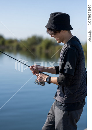 晴れた日の早朝に釣りを楽しむ若い男性 晴れた日の早朝に釣りを楽しむ若い男性 107992640