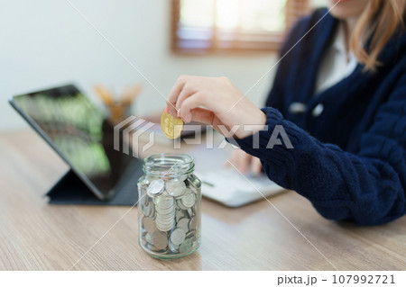 Cryptocurrency savings plan, Asian young woman saving digital coins into a piggy bank. Cryptocurrency savings plan, Asian young woman saving digital coins into a piggy bank. 107992721