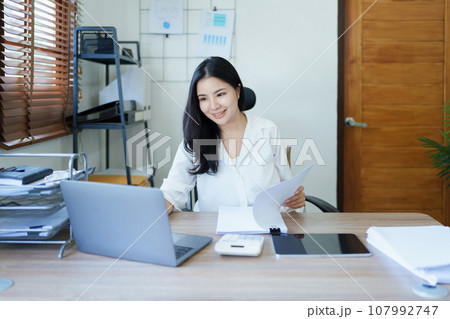 financial, Planning, Marketing and Accounting, portrait of Asian employee checking financial statements using documents, calculators and computer laptop at work. financial, Planning, Marketing and Accounting, portrait of Asian employee checking financial statements using documents, calculators and computer laptop at work. 107992747