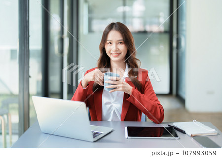 Portrait of a business woman talking on the computer and drinking coffee. Portrait of a business woman talking on the computer and drinking coffee. 107993059