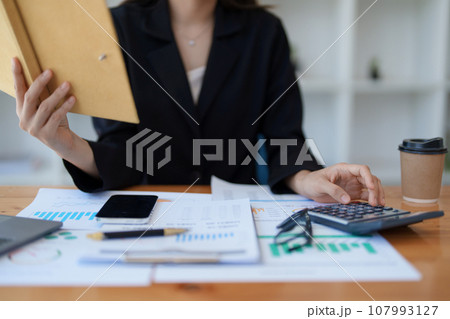 Young asian female work with financial papers at home count on calculator before paying taxes receipts online, planning budget glad to find chance for economy saving money, audit concepts. 107993127