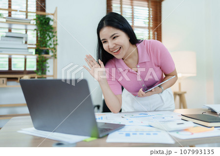 Portrait of a beautiful Asian teenage girl using computer for video conferencing at office. 107993135