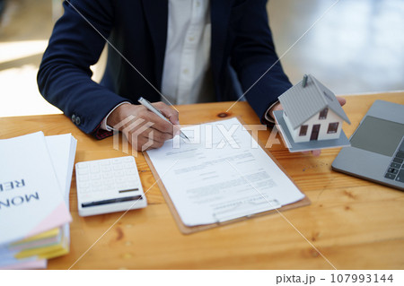 Guarantee, Mortgage, agreement, contract, Signing, Male client holding pen to reading agreement document to sign land loan with real estate agent or bank officer. Guarantee, Mortgage, agreement, contract, Signing, Male client holding pen to reading agreement document to sign land loan with real estate agent or bank officer. 107993144