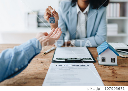 Female African american Real estate company to buy houses and land are delivering keys and houses to customers after agreeing to make a home purchase agreement and make a loan agreement Female African american Real estate company to buy houses and land are delivering keys and houses to customers after agreeing to make a home purchase agreement and make a loan agreement 107993671