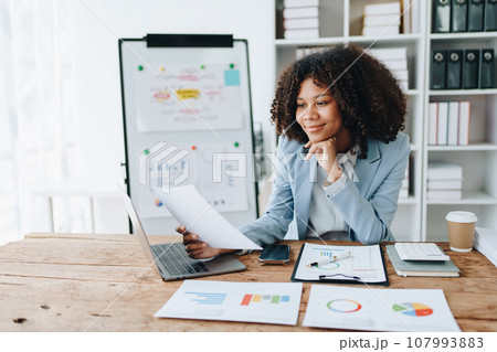 financial, Planning, Marketing and Accounting, portrait of african american employee checking financial statements using documents and calculators at work. 107993883