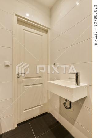 a white bathroom with black tile flooring and an open door leading to the toilet area in the shower room a white bathroom with black tile flooring and an open door leading to the toilet area in the shower room 107993928