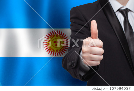 Argentine concept. Businessman showing thumb up on the background of flag of Argentina Argentine concept. Businessman showing thumb up on the background of flag of Argentina 107994057
