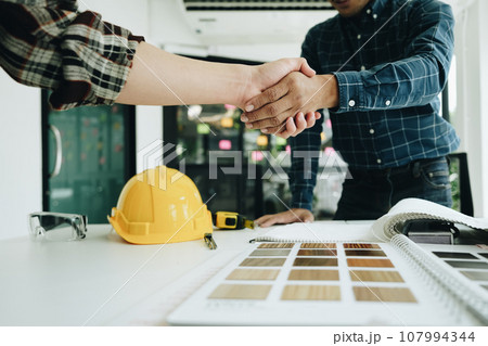 Engineers, designers and interior designers are handshake shack hands deal finalizing the design of interiors by discussing selecting materials and colors to design rooms to present to clients 107994344