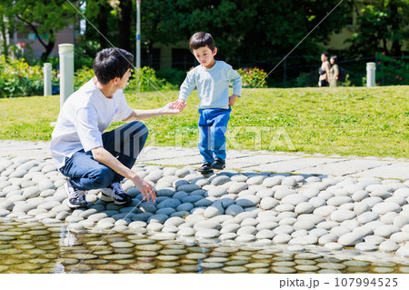小川でお父さんと水遊びをする子供 107994525