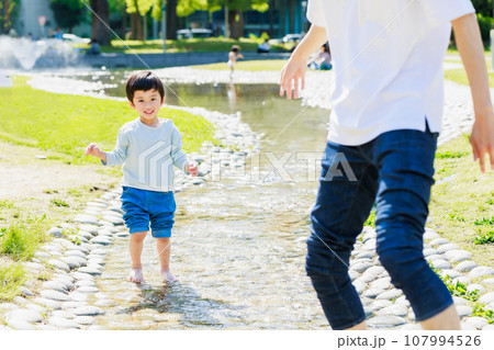 小川でお父さんと水遊びをする子供 107994526